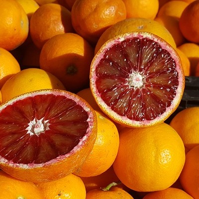 dark red blood orange cut open on top of other oranges