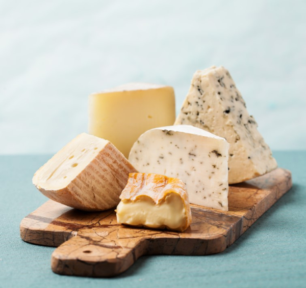 selection of cut cheeses on wooden board