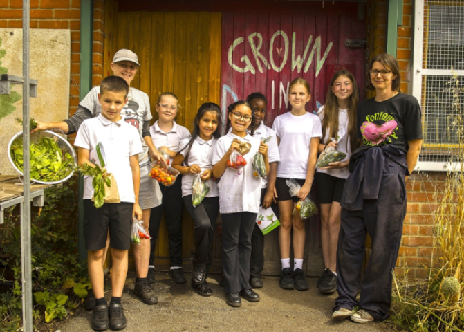 Alice Ashlea and school kids holding bags of organic leaves