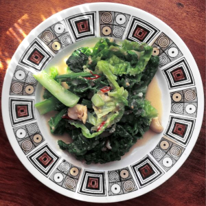 Dish of savoy cabbage and tatsoi on patterned plate on wooden table